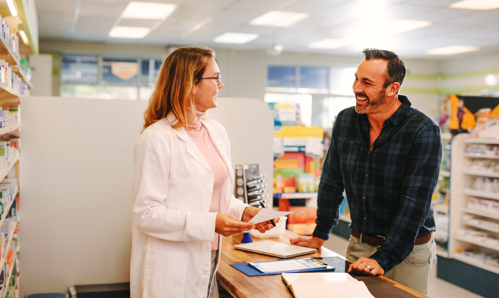 Female pharmacist wearing eyeglasses talking with an adult man smiling